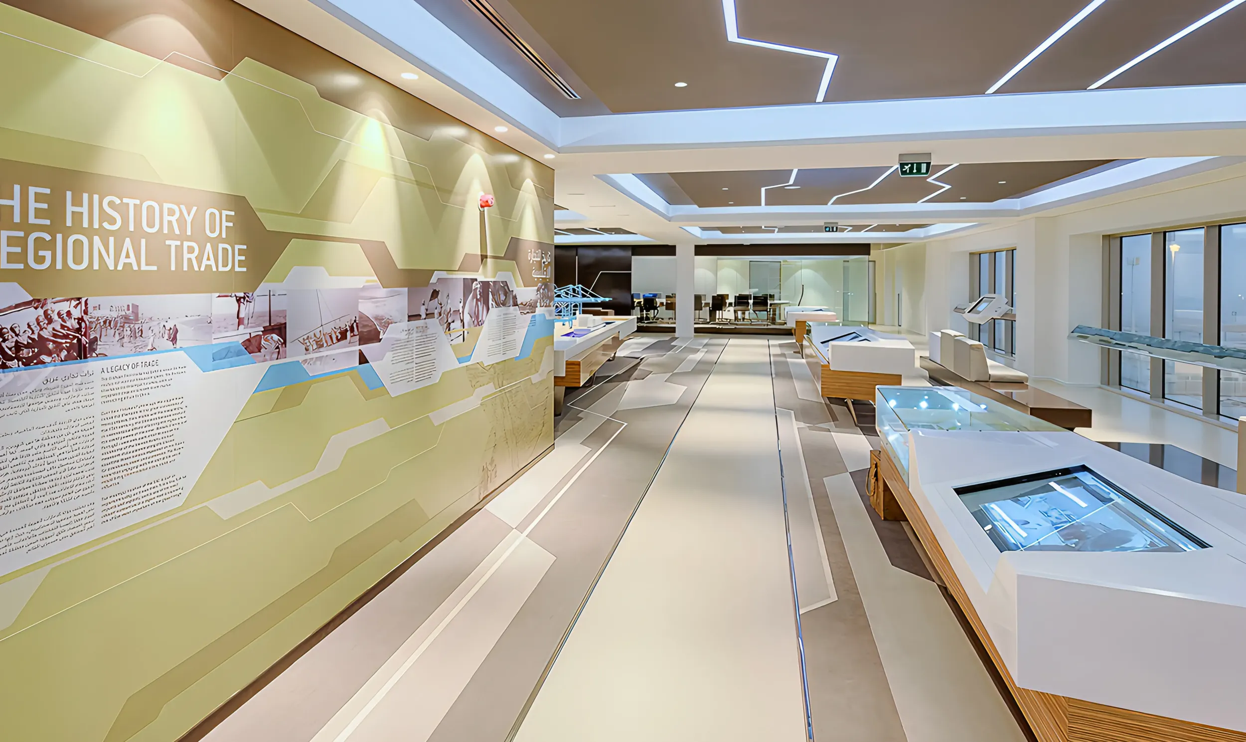 Interior of Abu Dhabi Ports visitor center with "THE HISTORY OF REGIONAL TRADE" wall graphic and interactive displays. Skyne, a creative agency, specializes in experiential branding and visitor center design for clients in Dubai, Riyadh, and Jeddah.