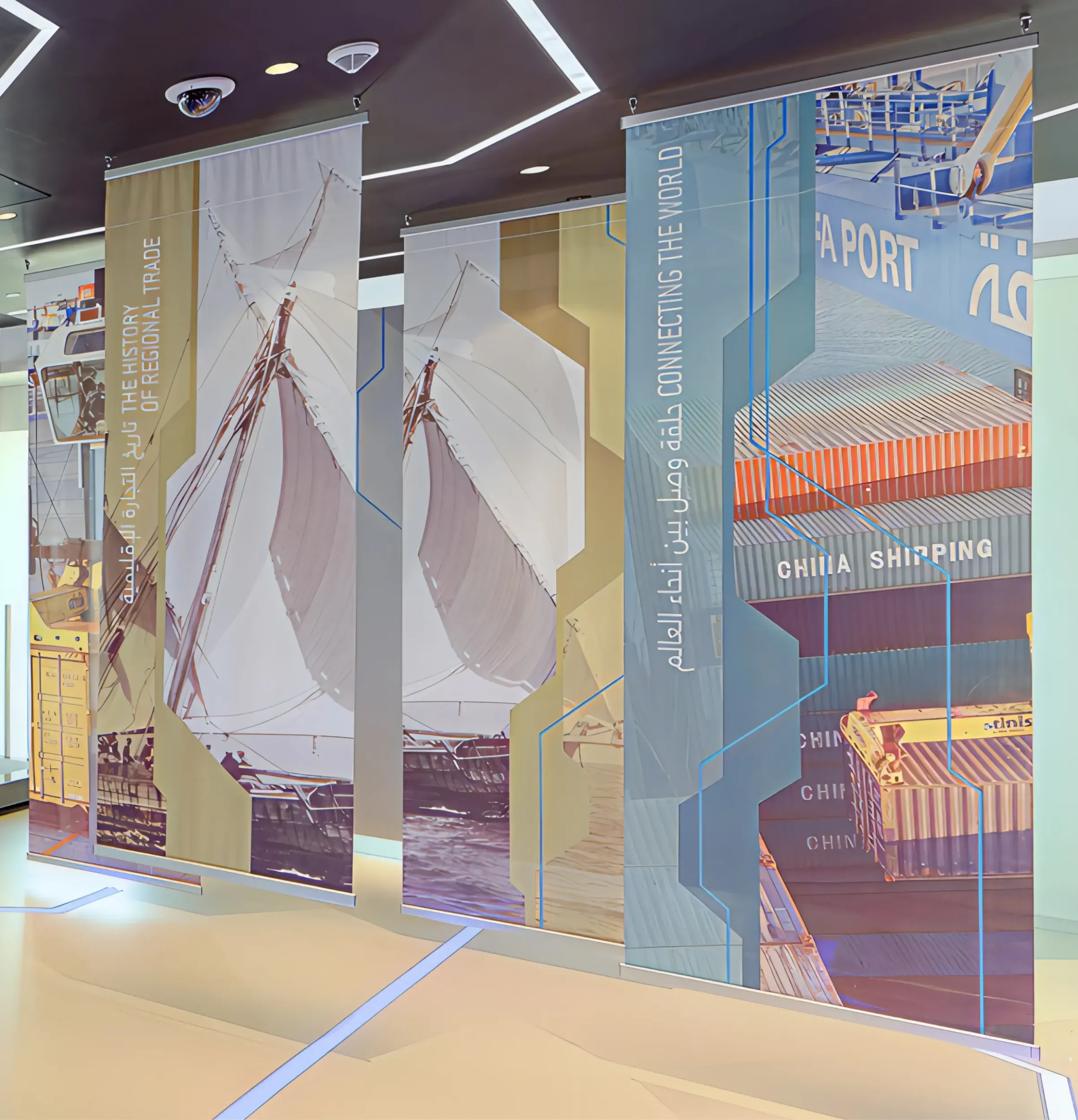 Hanging banners in Abu Dhabi Ports visitor center, illustrating regional trade history with dhows and modern shipping containers