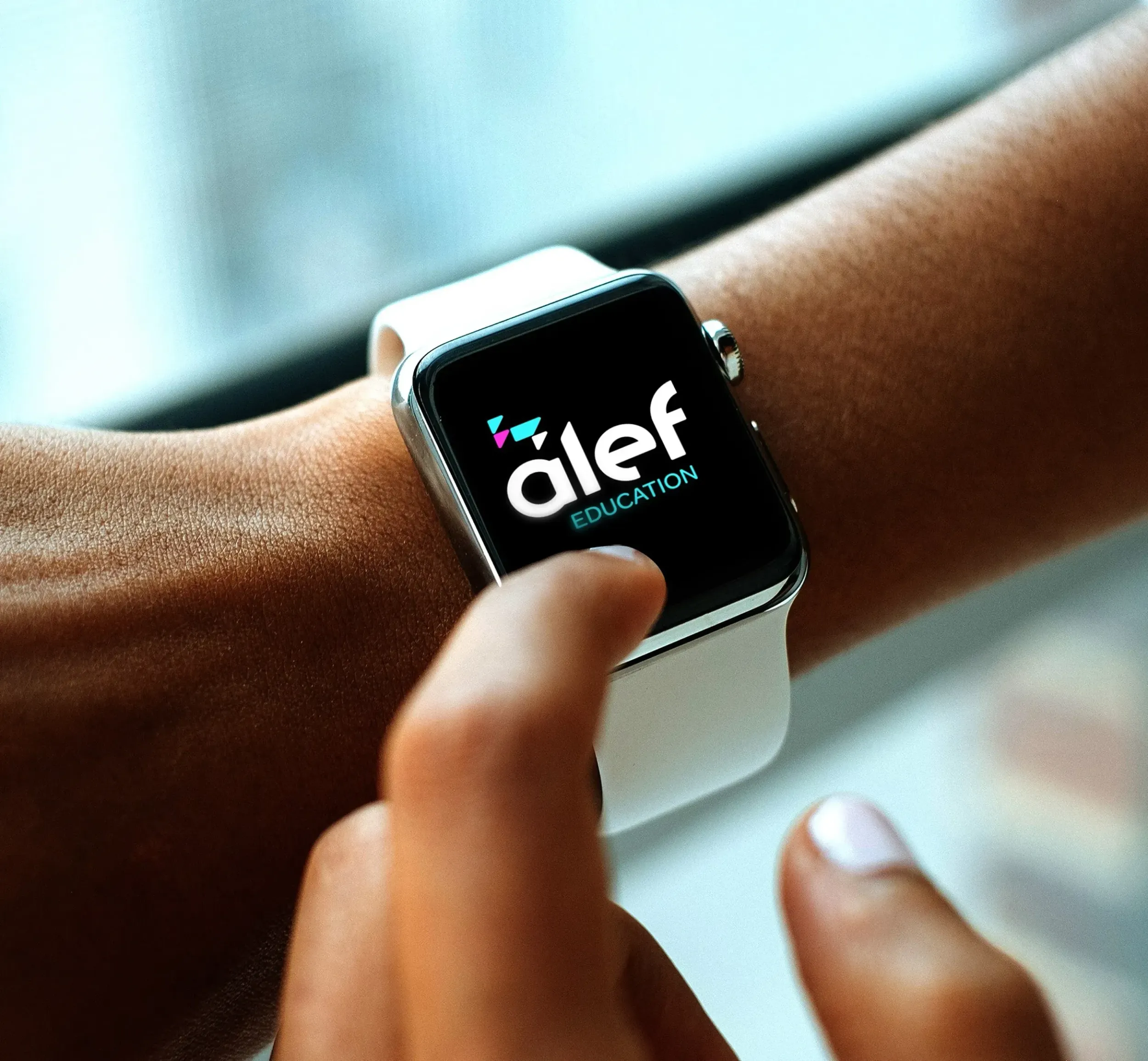 A hand interacting with an Apple Watch displaying the Alef Education logo, symbolizing the accessibility and integration of their digital learning platform across various devices, a testament to Skyne's forward-thinking branding.