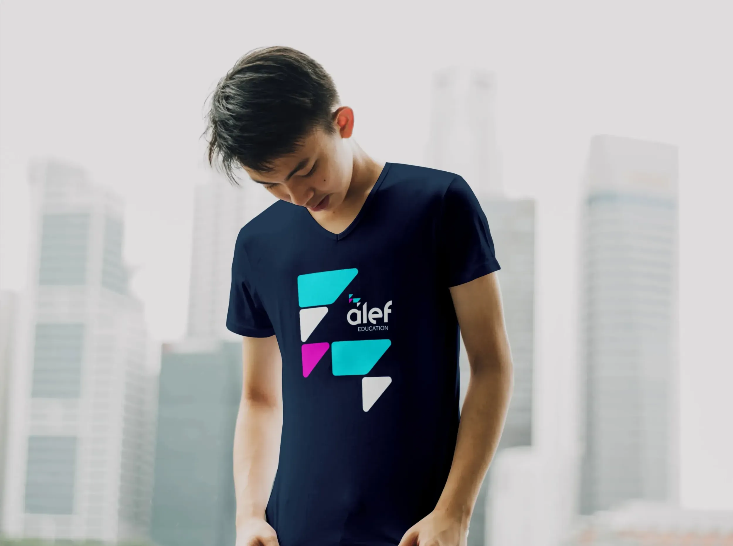 A person wearing a dark blue t-shirt with the Alef Education logo, showcasing the brand's identity and the tangible results of Skyne's branding and packaging design for educational institutions.