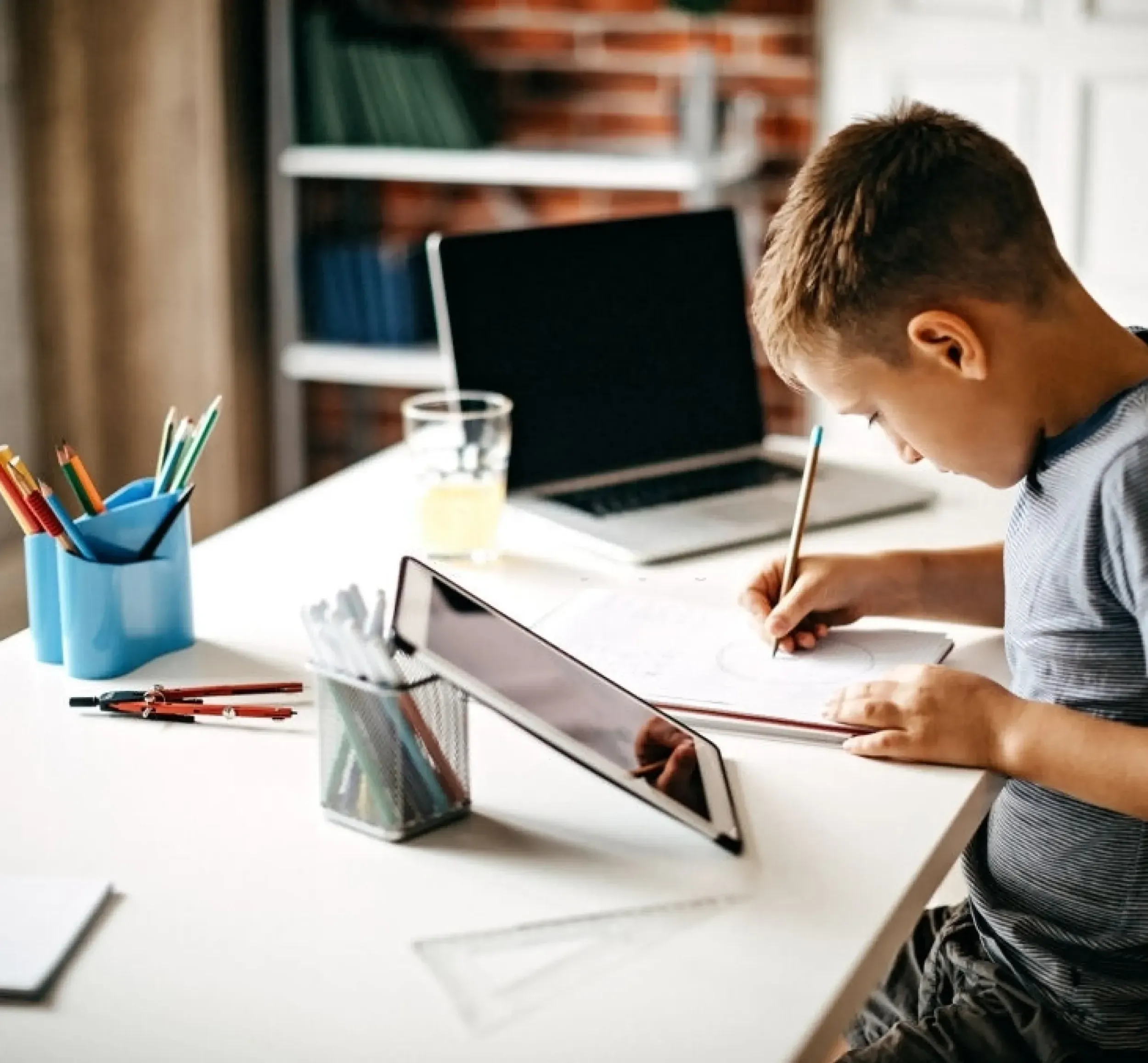 A young student engaged in digital learning on a tablet and laptop, illustrating Alef Education's personalized education experiences and Skyne's role in branding for educational technology.