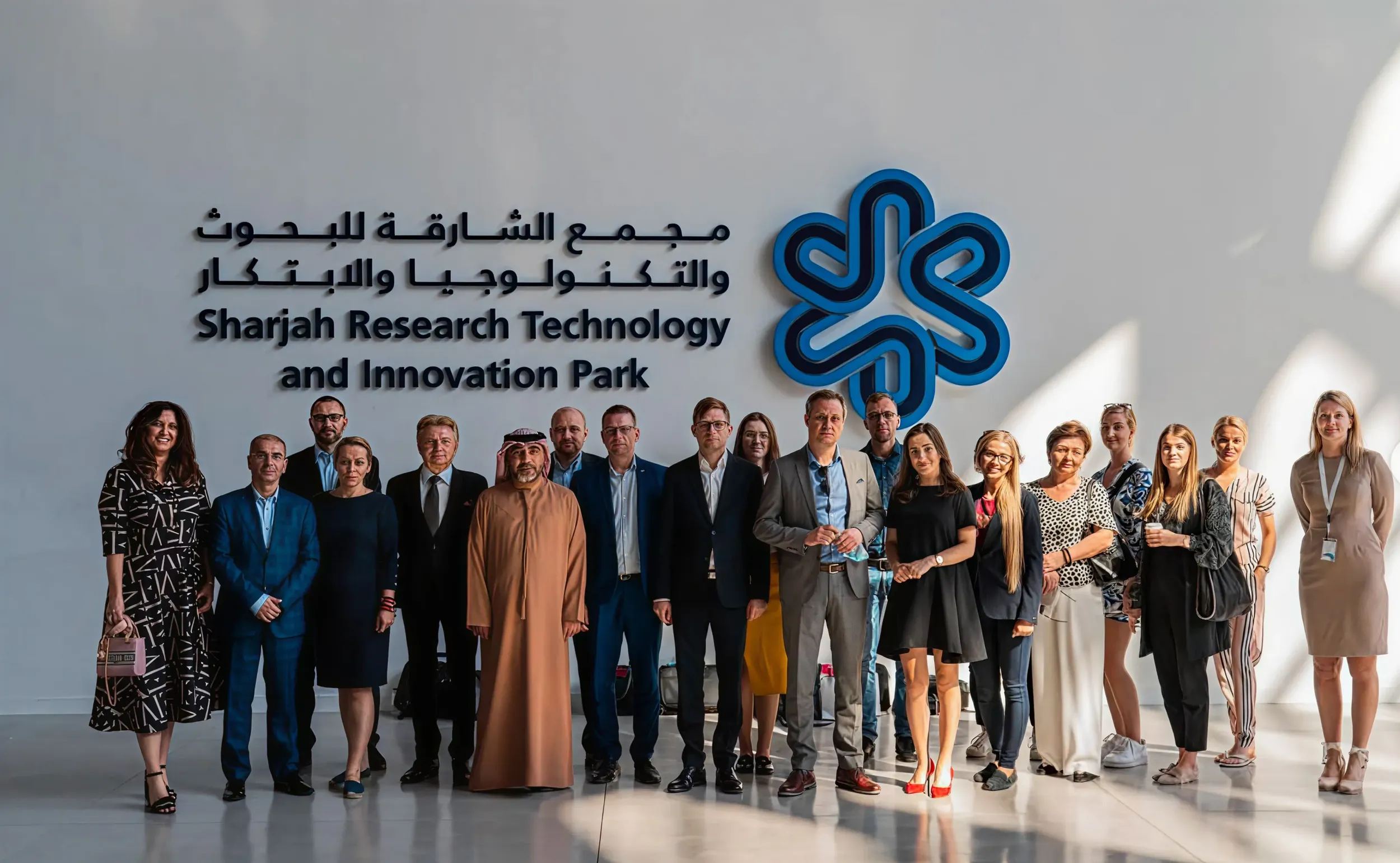 A group photo of professionals at the Sharjah Research Technology and Innovation Park, with the SRTIP branding, designed by Skyne branding agency