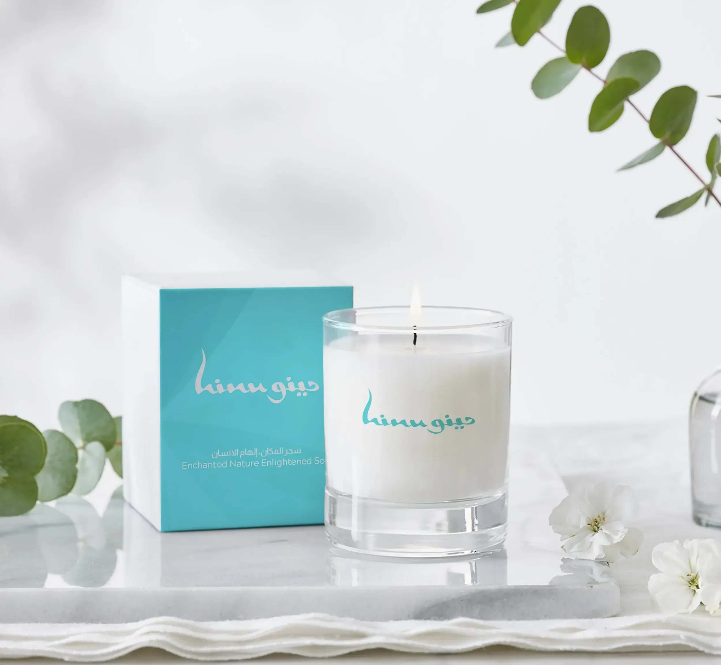  Hinu Bay branded candle and packaging in teal and white, symbolizing natural luxury. Skyne creative agency provides comprehensive branding for premium products and destinations in Dubai.