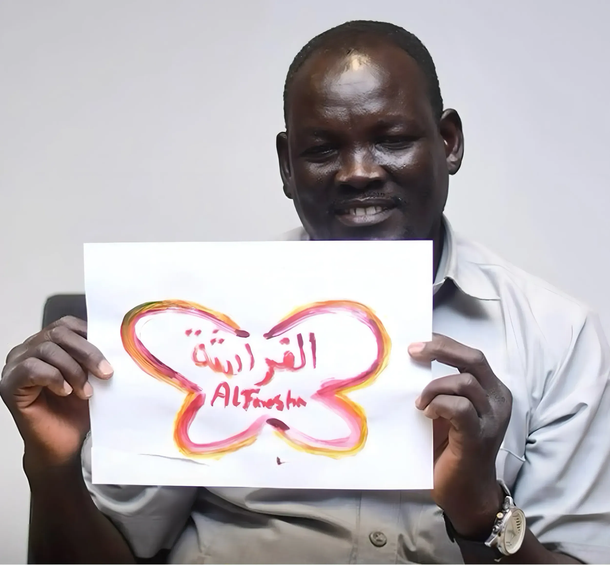 Man holding a hand-drawn Al Farasha butterfly logo, symbolizing community engagement. Skyne, a creative agency, fostered internal and external brand embrace.