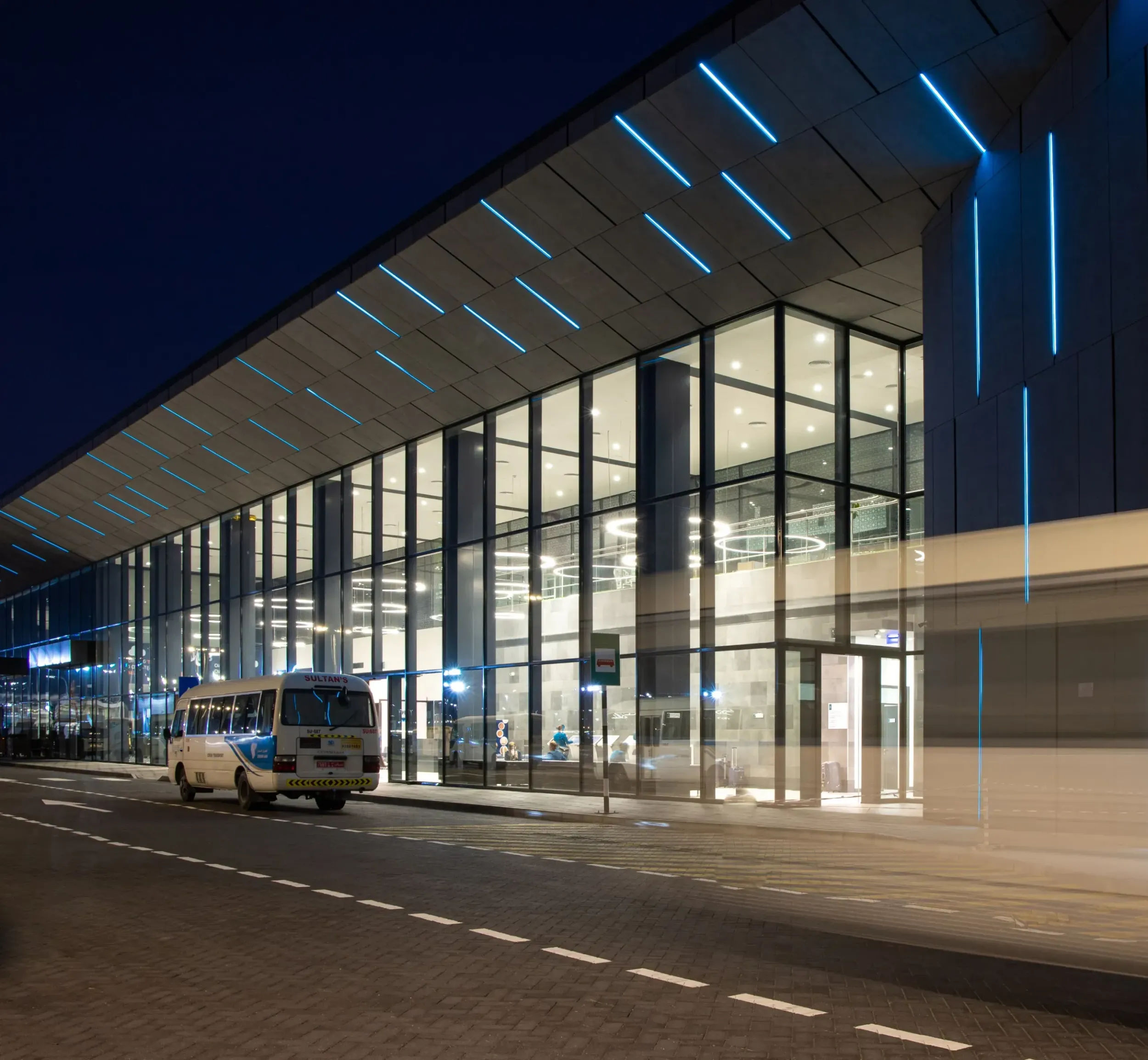 Modern building exterior at night with blue accent lighting, showcasing F&M International projects. Skyne, a creative agency, highlights F&M's architectural expertise. 