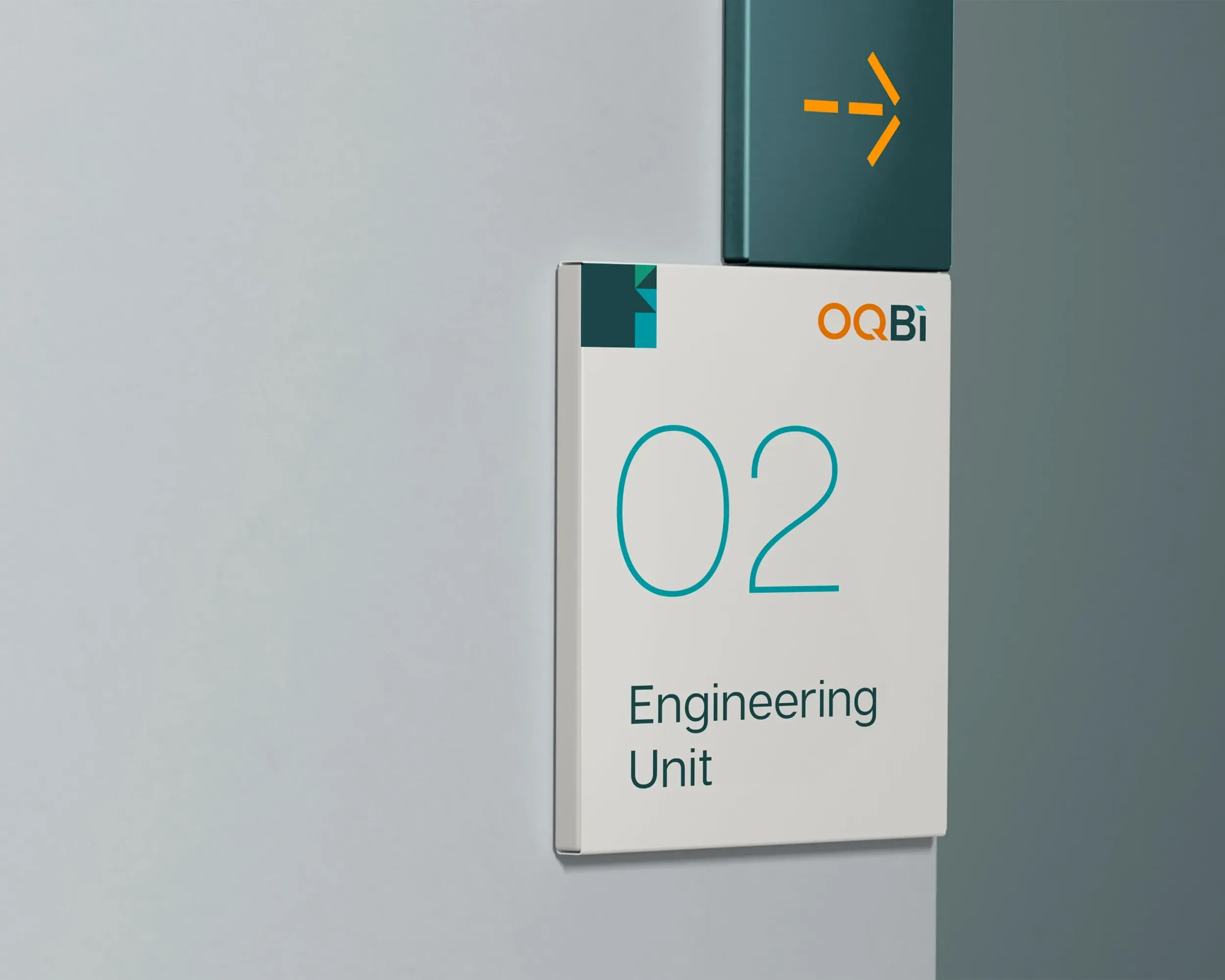 OQBi office sign for "Engineering Unit" with logo and wayfinding arrow. Skyne provides comprehensive signage and environmental branding solutions for corporate clients in Dubai, Riyadh, and Jeddah.