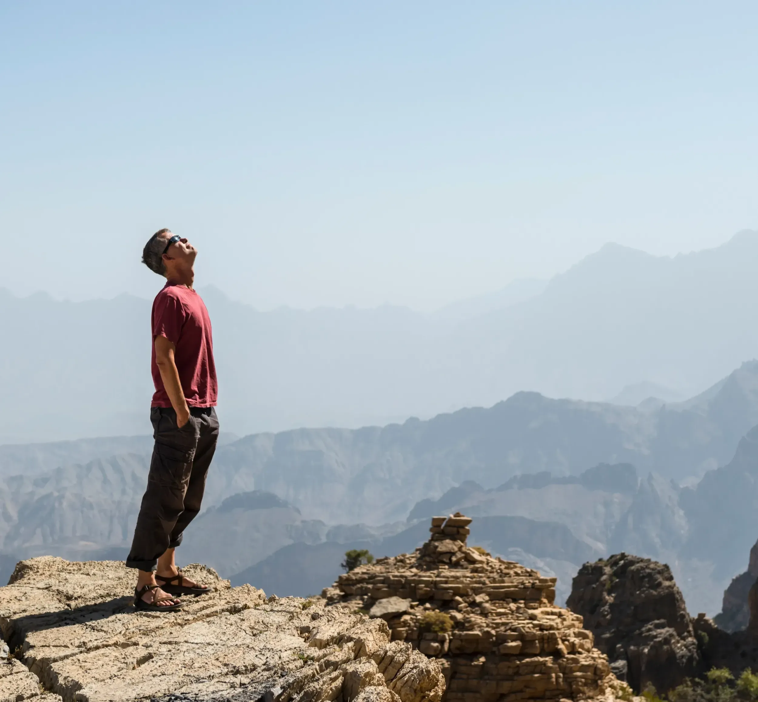 A man on a mountain peak, looking at the sky and distant ranges. This image captures the adventure and exploration central to the Naseem brand by Skyne, a leading branding and creative agency.