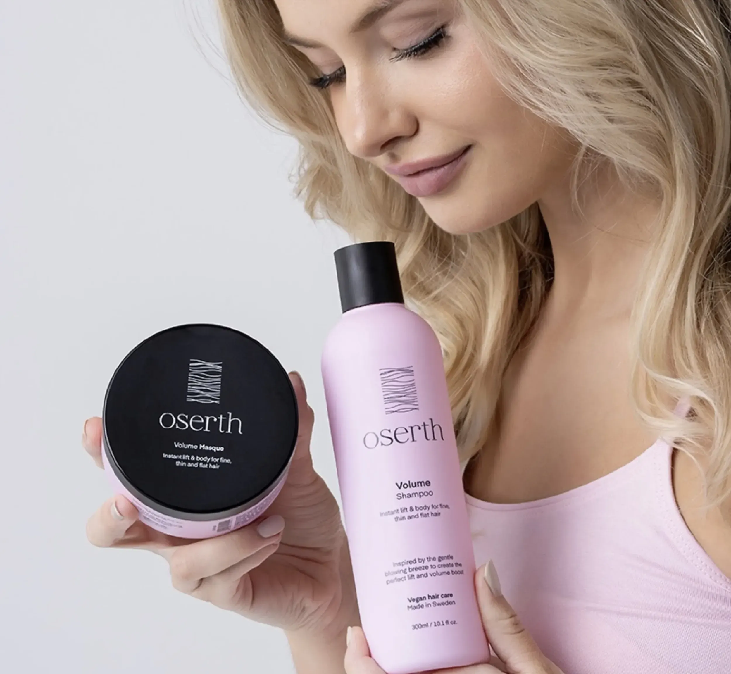 Woman holding Oserth Volume Masque and Shampoo in pink packaging, highlighting product benefits and elegant packaging design by Skyne, a creative agency specializing in packaging design.