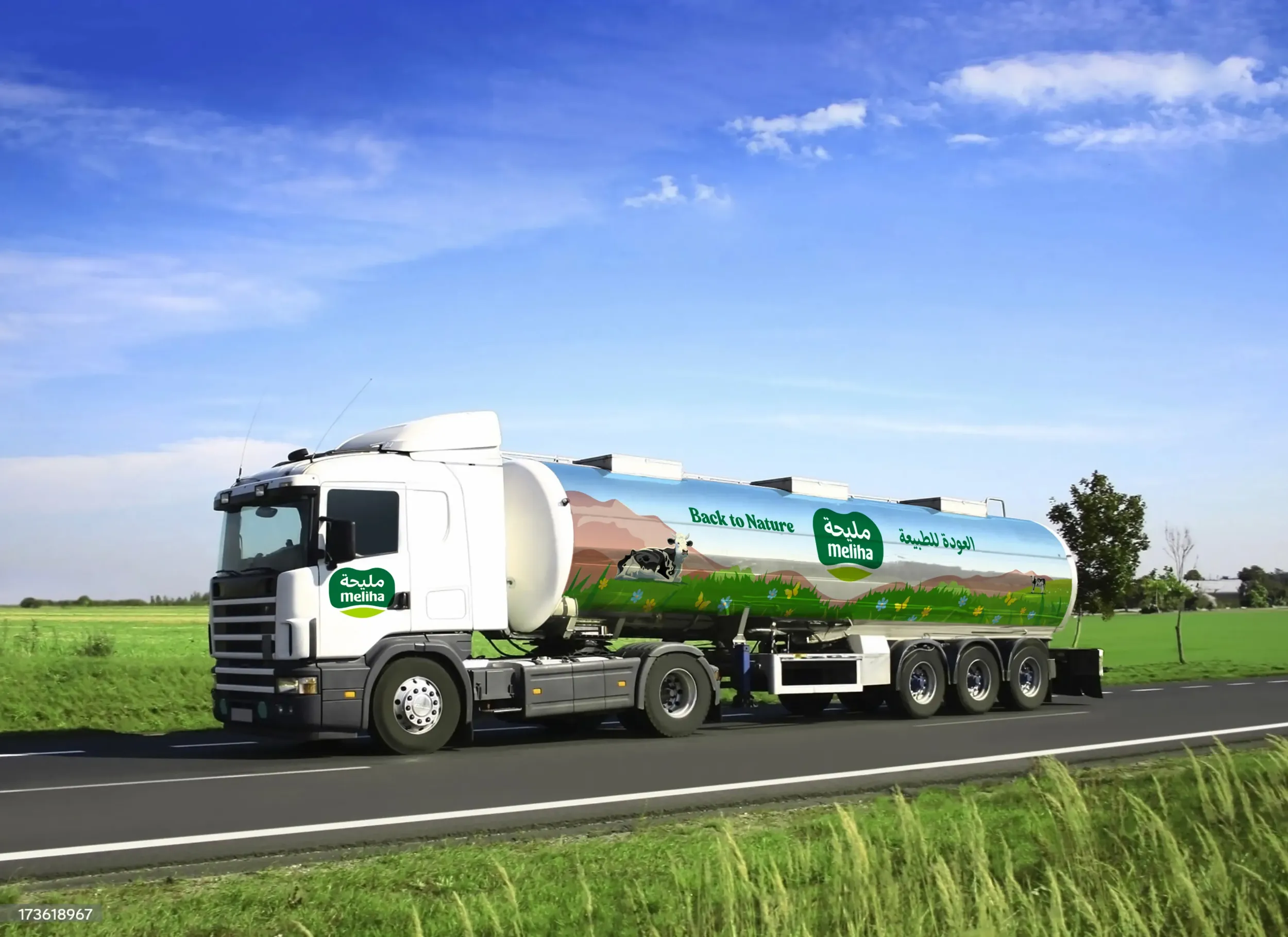 Milk tanker truck with 'Meliha Organic' branding driving on a rural road beside green fields under a clear blue sky.