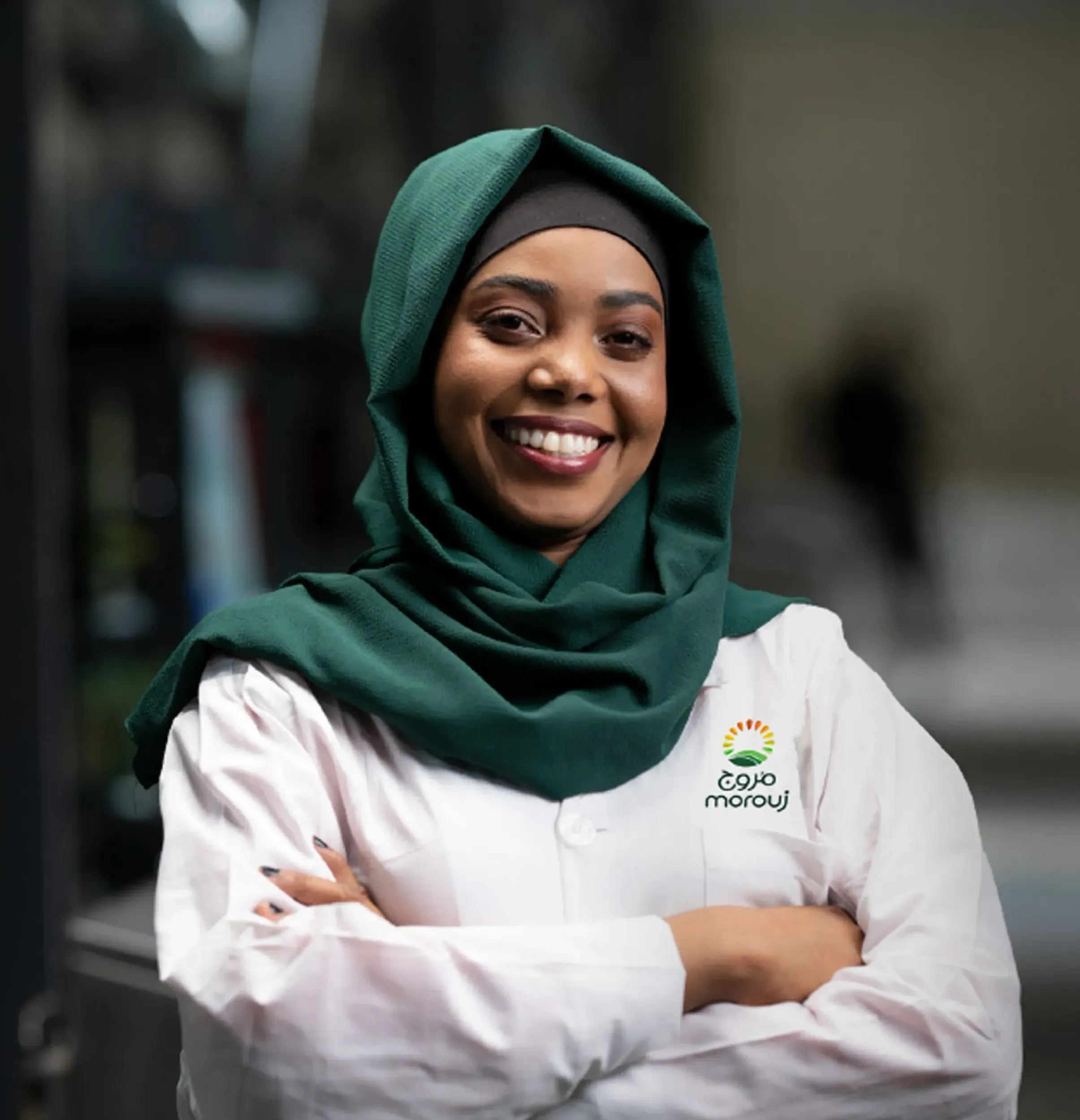 Smiling female employee in Marooj uniform and green hijab, portrait photography by Skyne branding agency