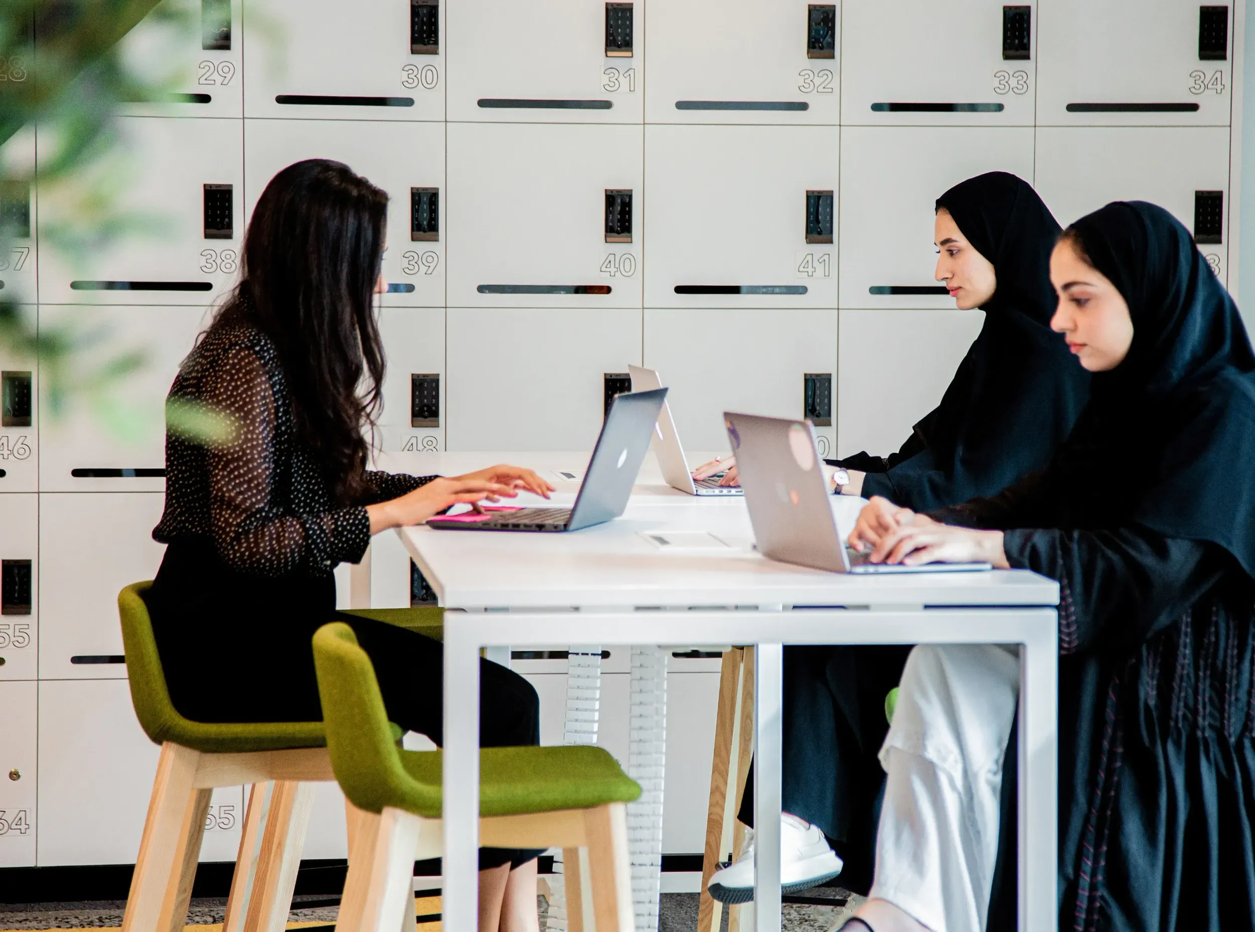 Three women working on laptops in a modern workspace at the Sharjah Research Technology and Innovation Park, part of the STRIP branding campaign by Skyne branding agency.