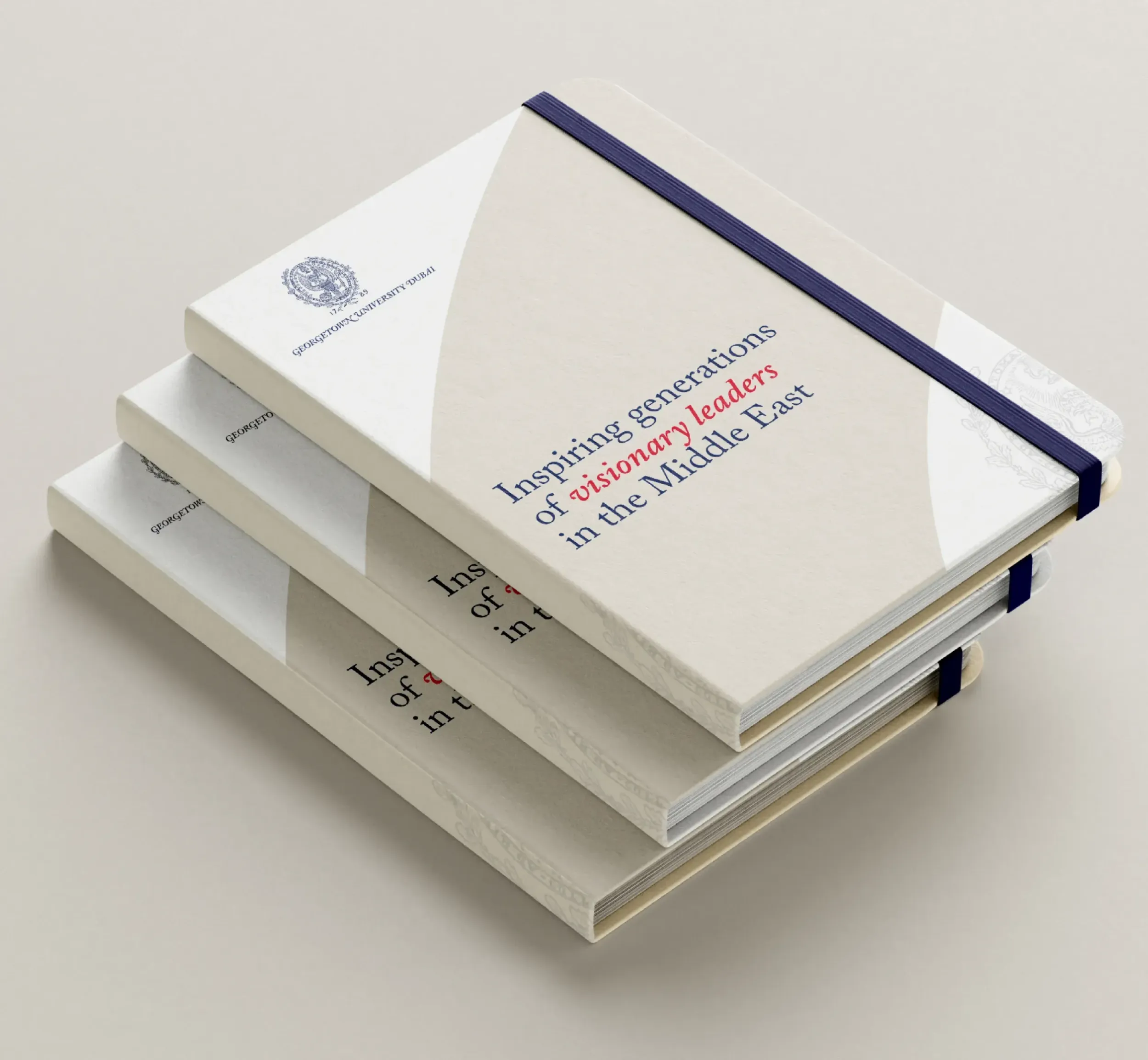  Stack of three notebooks branded with Georgetown University Dubai, featuring tagline "Inspiring generations of visionary leaders in the Middle East." Skyne develops branding for leadership programs in Dubai, Riyadh, and Jeddah.