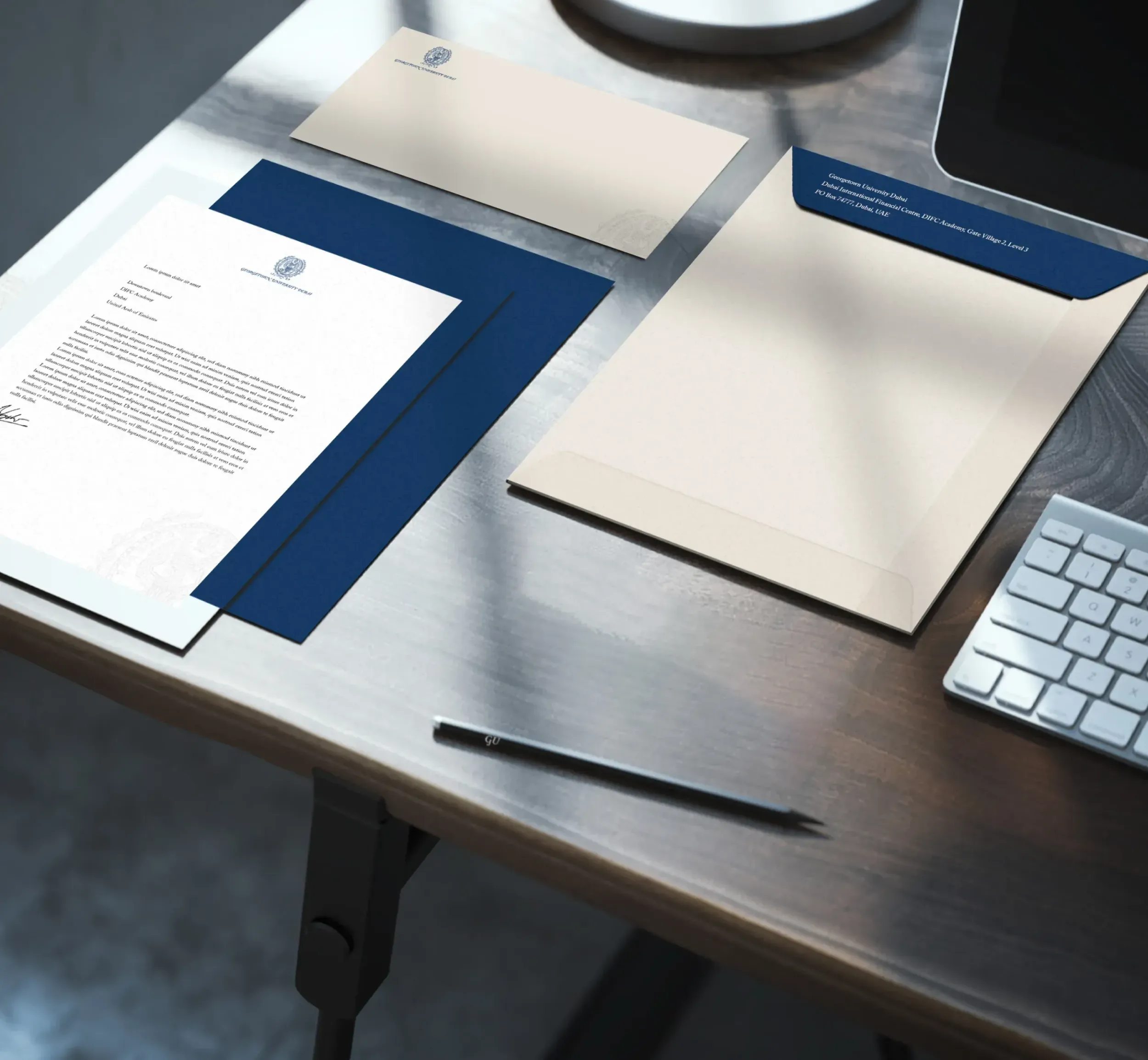 Flat lay of Georgetown University Dubai branded stationery, including letterhead, envelope, and pen. Skyne designs comprehensive brand collateral and stationery for educational institutions in Dubai, Riyadh, and Jeddah.